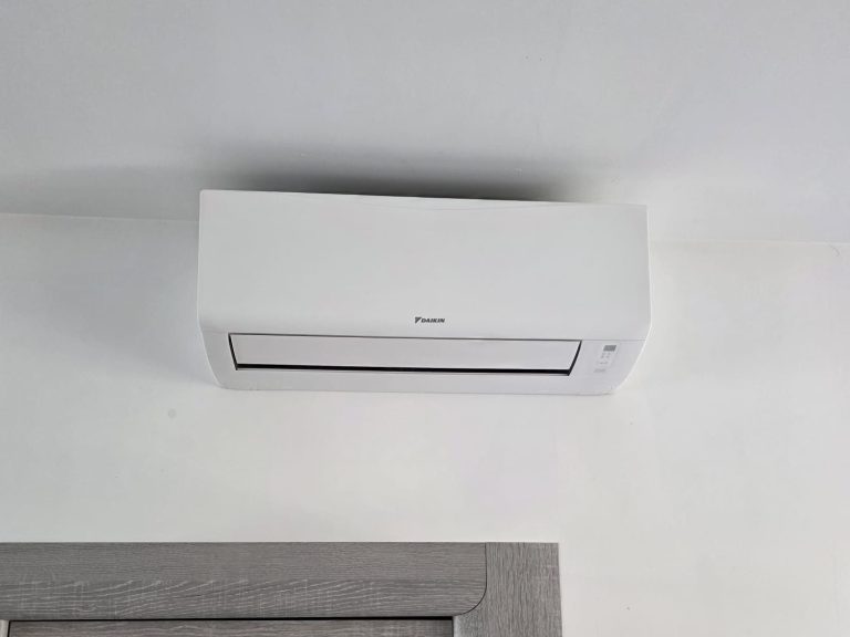 Climatiseur mural blanc installé au-dessus d'une porte dans une pièce.